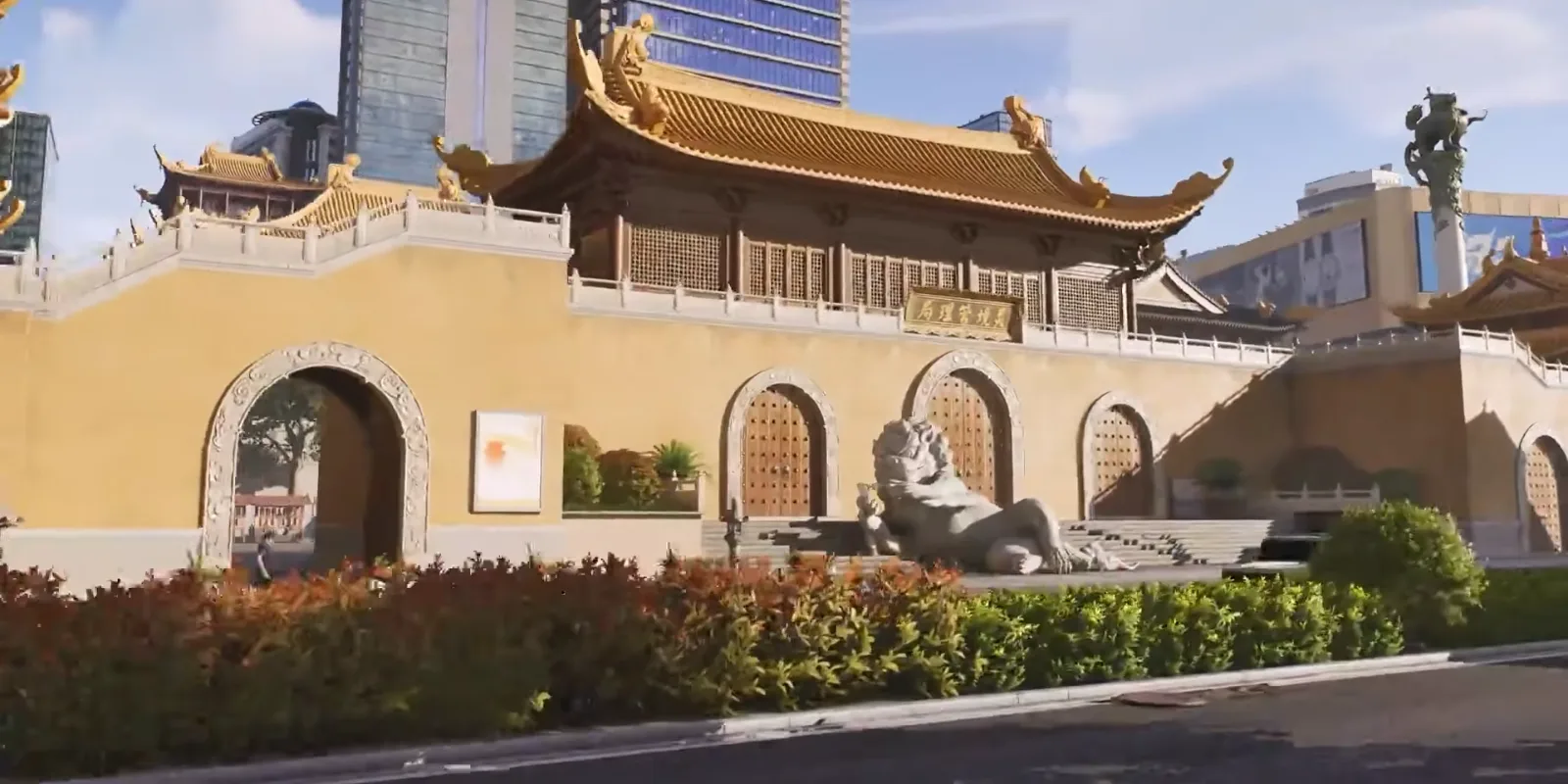 Ananta Chongxiao temple with ochre walls, a golden tiled roof and a stone lion, glass office towers rising behind it